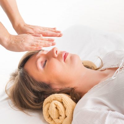 Professional Reiki healer doing reiki treatment to young woman